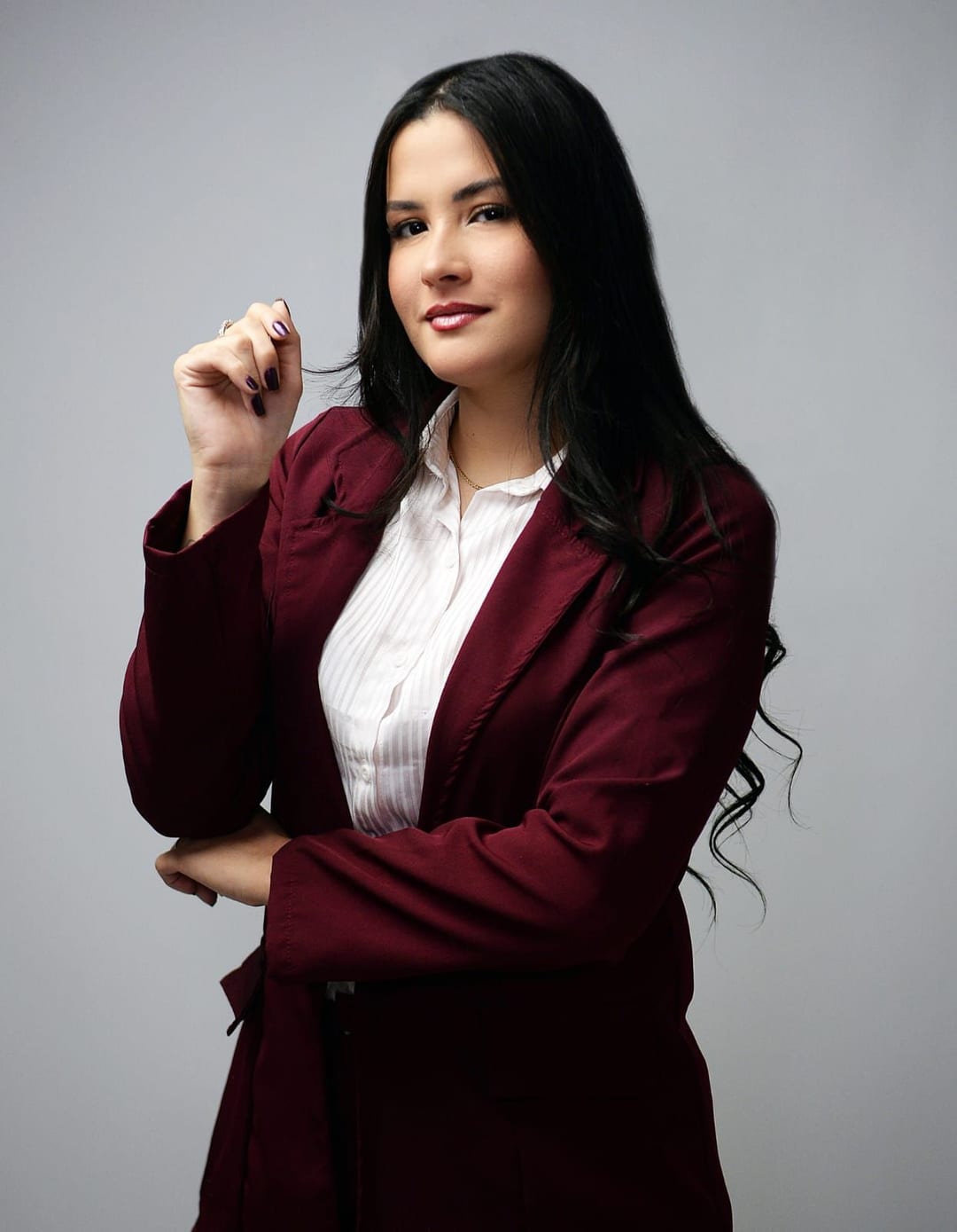 Bianca Camargo, sorridente, vestindo blazer bordô e camisa branca, transmitindo confiança e elegância